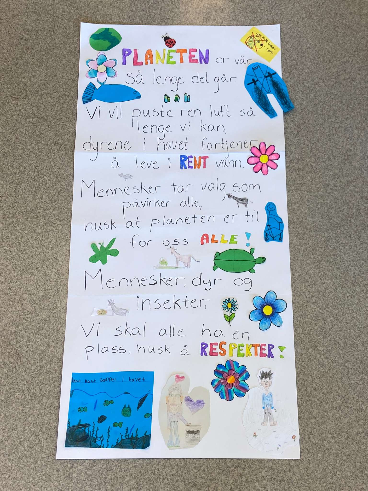 En fargerik plakat med tekst om at planeten er til for oss alle, mennesker, dyr og insekter. Fotografi av plakat.