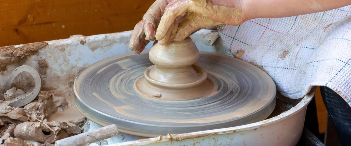 A potter's hands shaping clay on the wheel