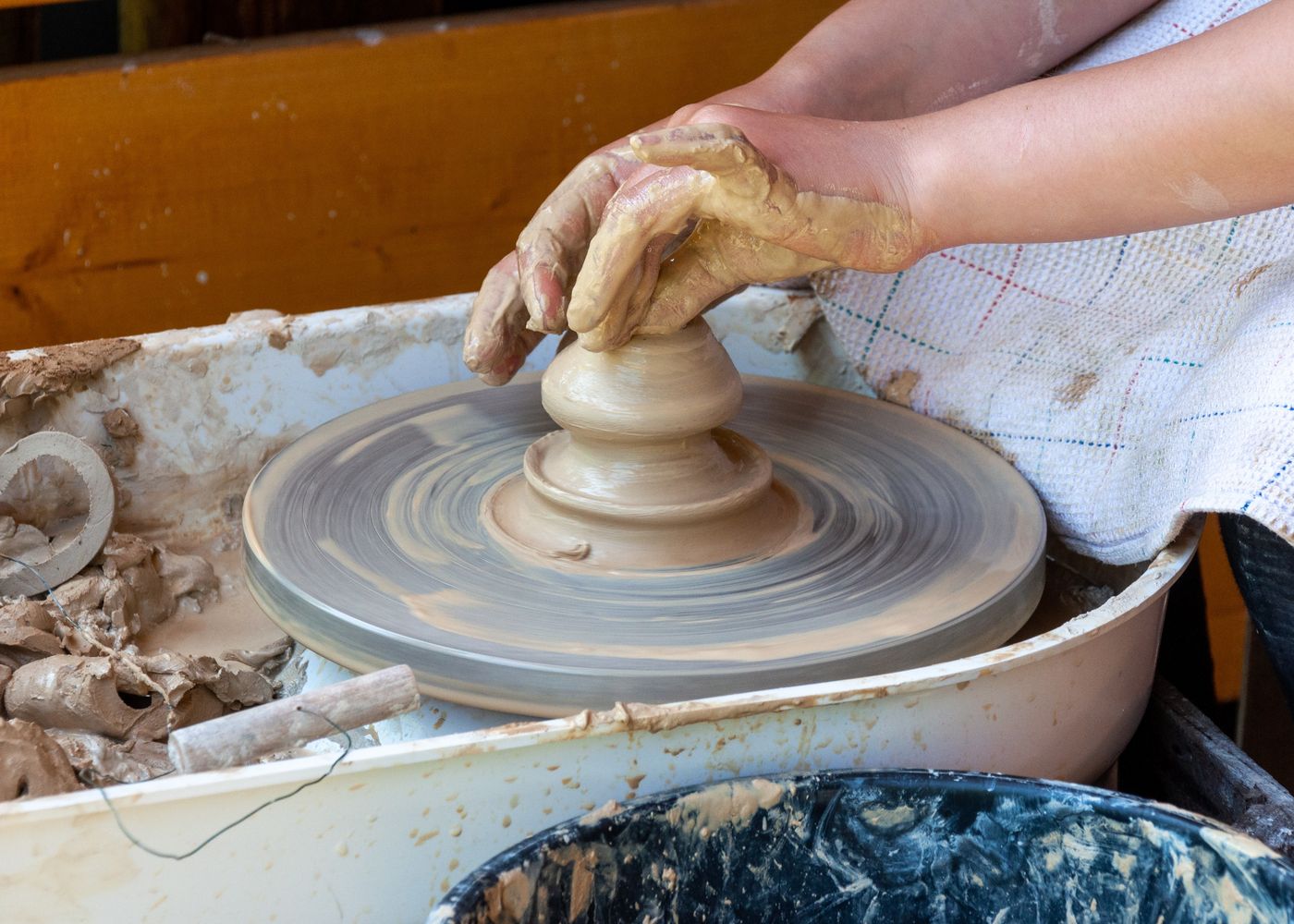 A potter's hands shaping clay on the wheel