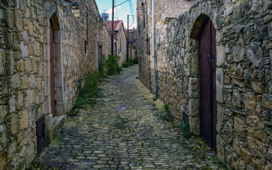An empty cobbled lane between stone houses in a quiet village