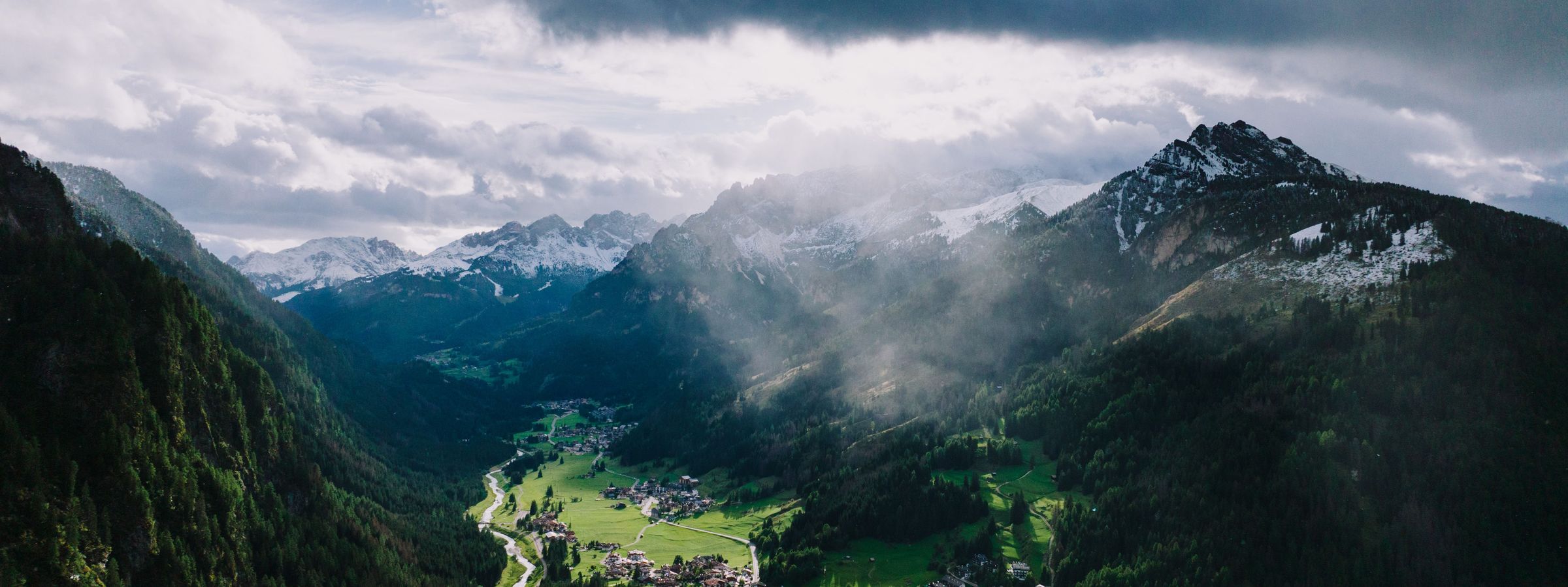 An Alpine valley with a village beneath snow-streaked peaks