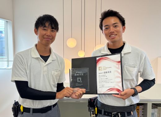 賞状とトロフィーを持った男性二人が嬉しそうに笑顔を向けている写真