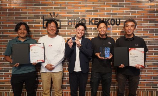 5人の男性がそれぞれに賞状とトロフィーを持ち、こちらに笑顔を向けている写真