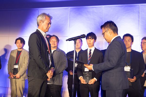 ステージ上で書状を手渡しされる男性の様子