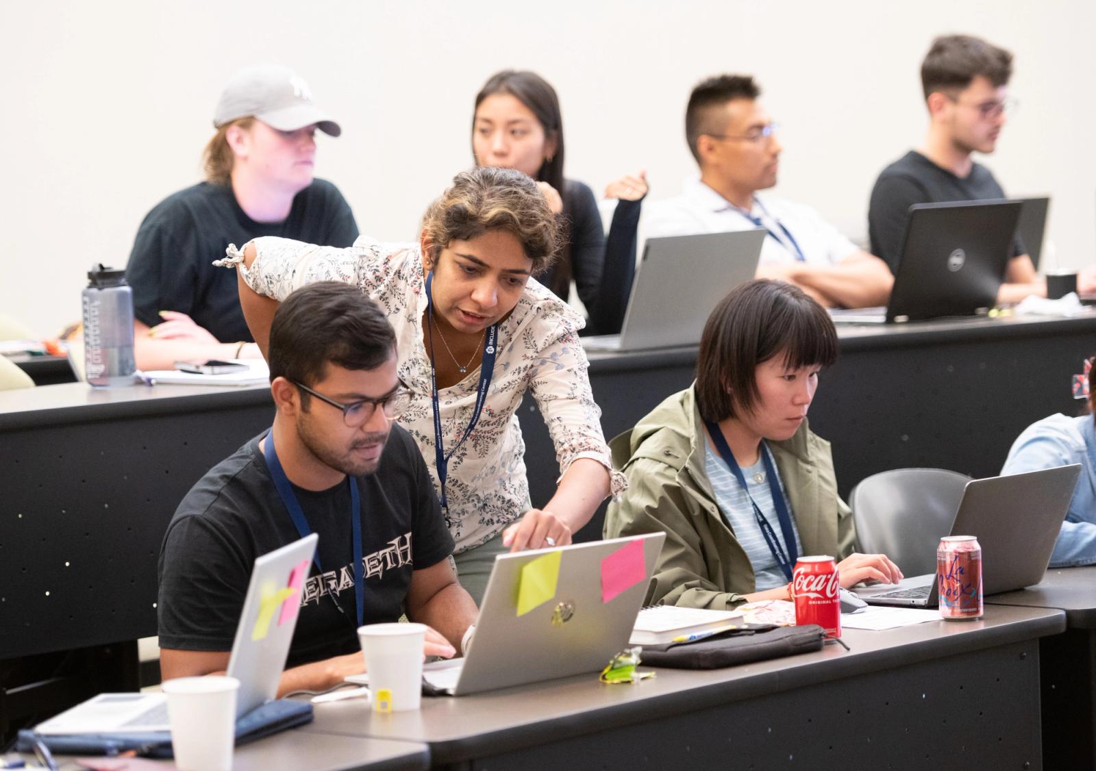 DS3 instructor addressing a question of a student sitting in the classroom at their laptop