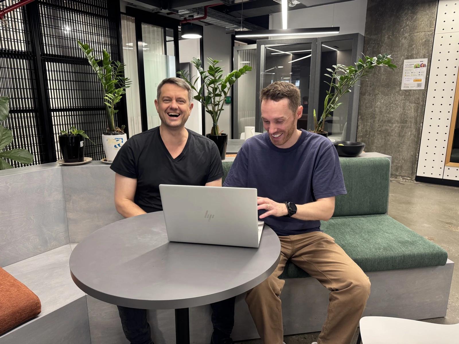 Travis Clapp and Alex Hey laughing as they work together on a laptop in Perth