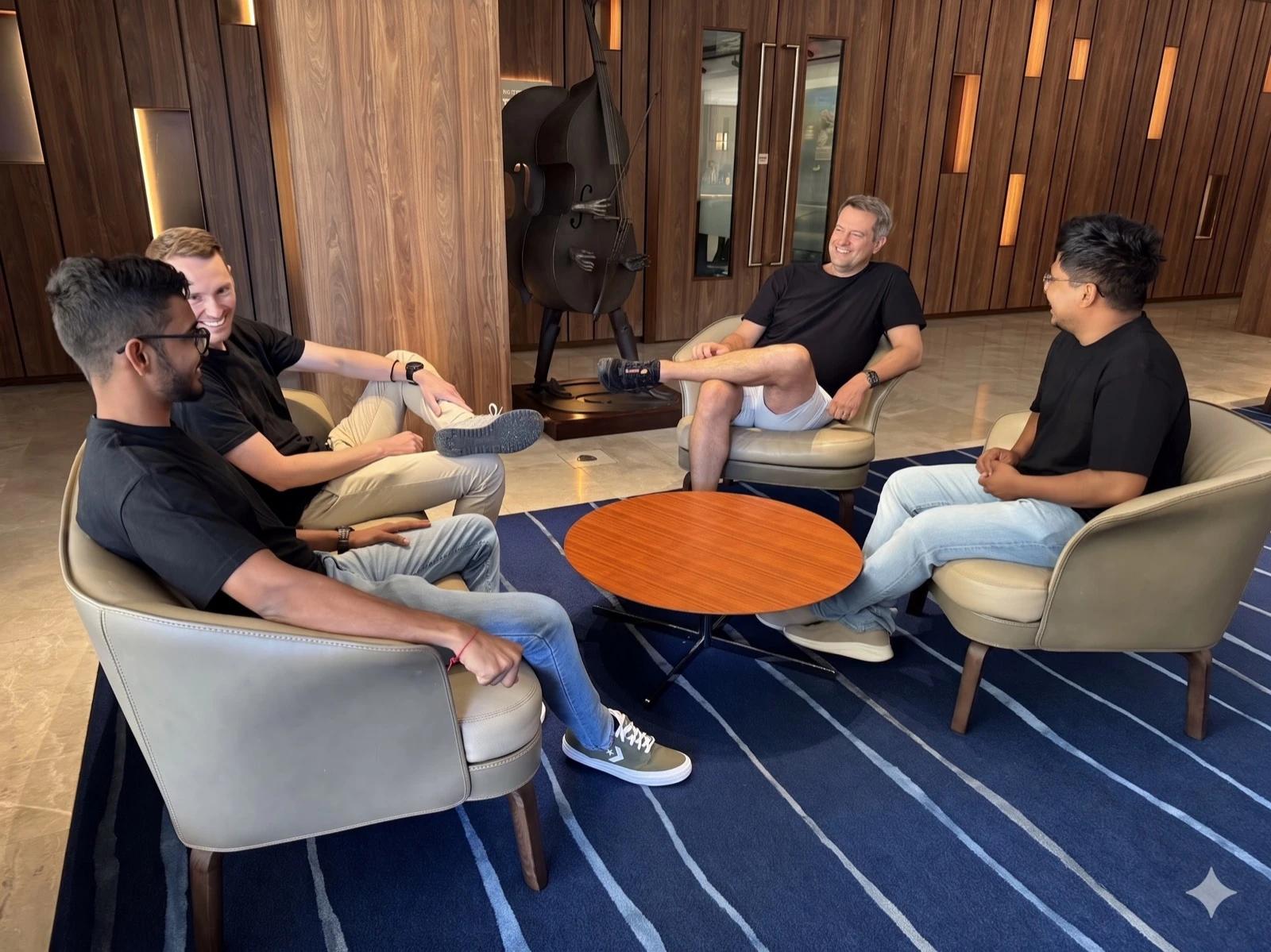 Travis Clapp, Alex Hey and 2 teammates talking in armchairs in a lounge