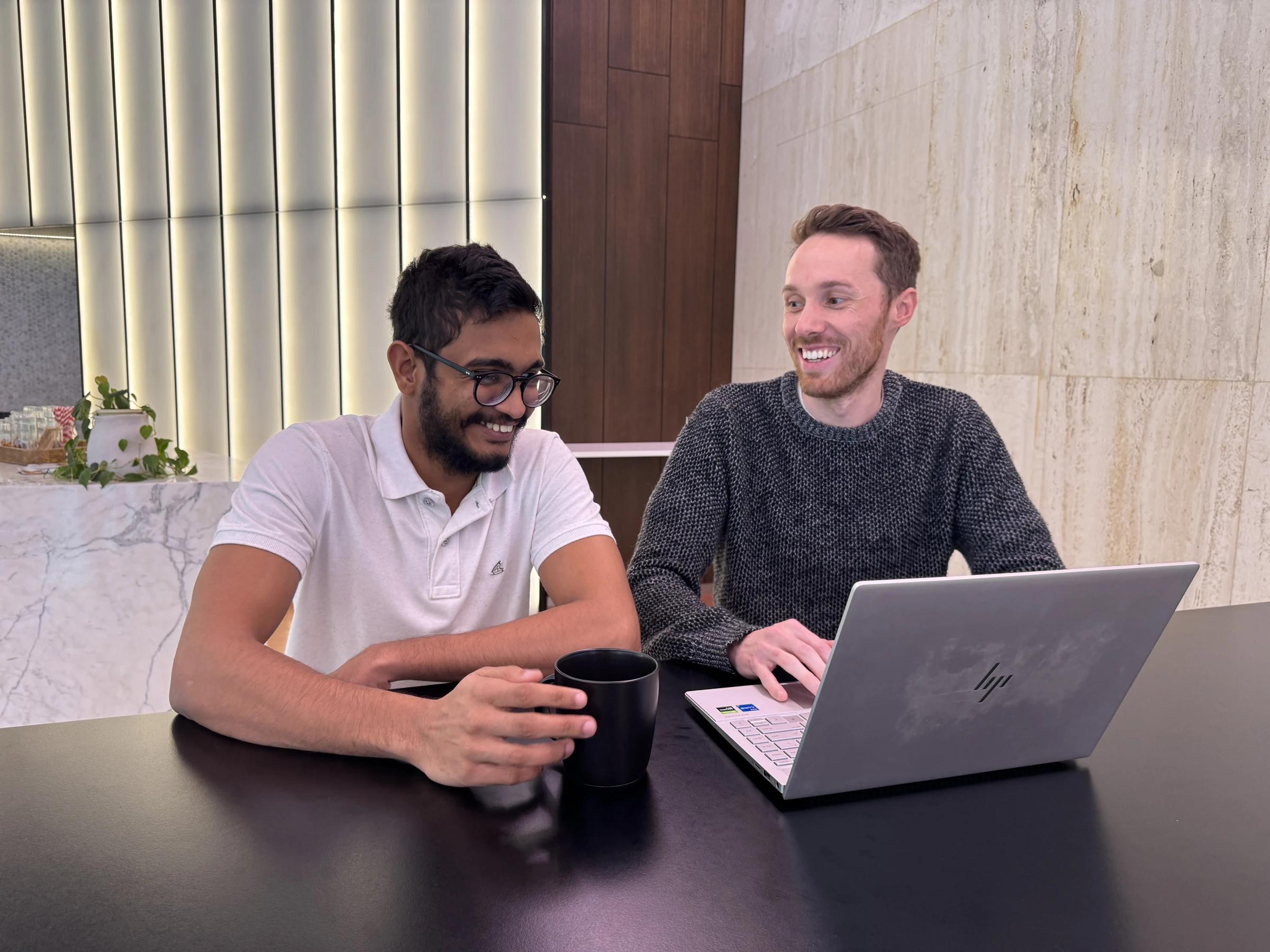 2 Coursebox AI teammates sharing an AI workflow on a laptop