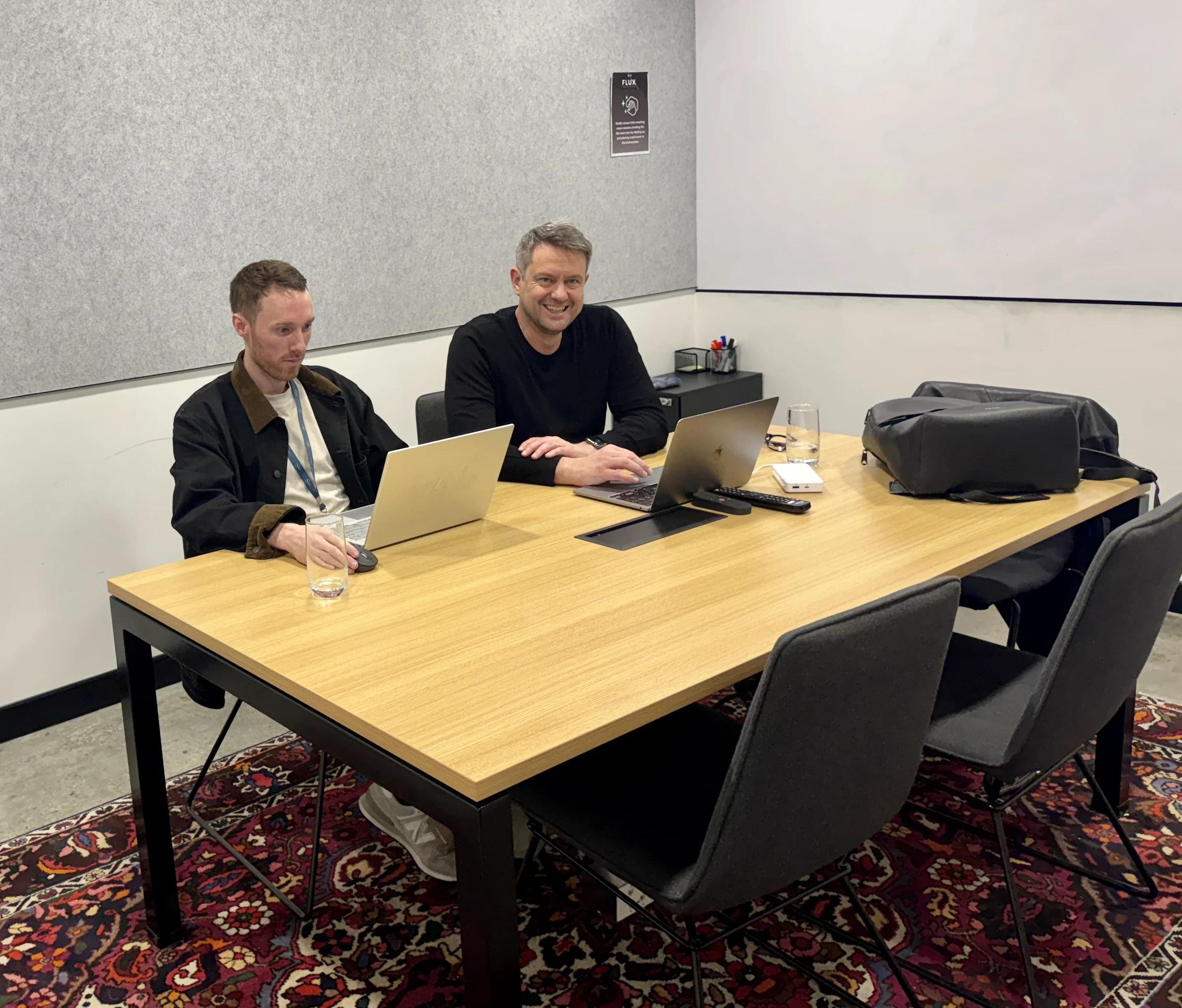 2 Coursebox AI teammates testing a new feature idea on their laptops in a meeting room