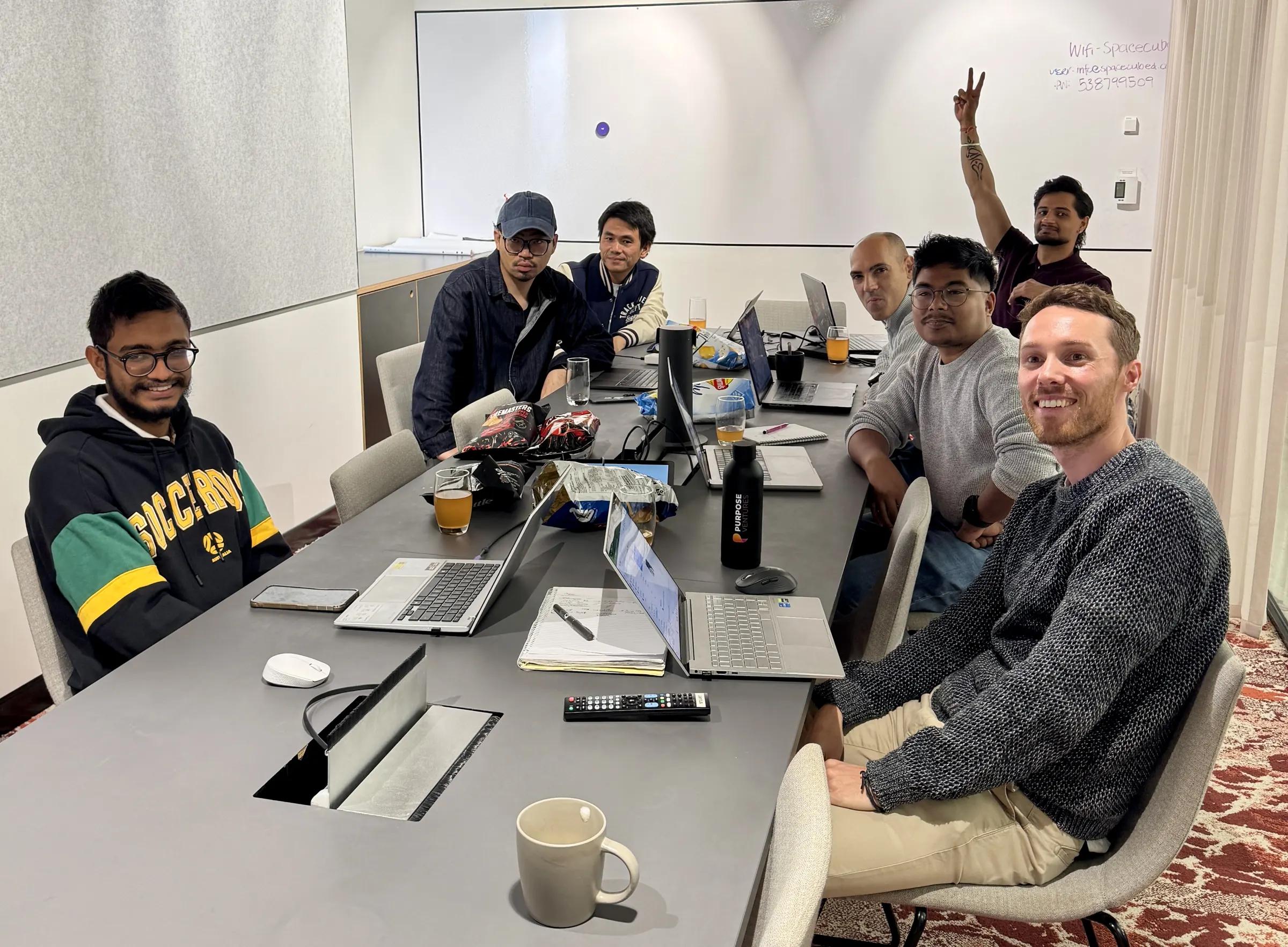 The Coursebox AI team working on laptops around a meeting room table during a learning session