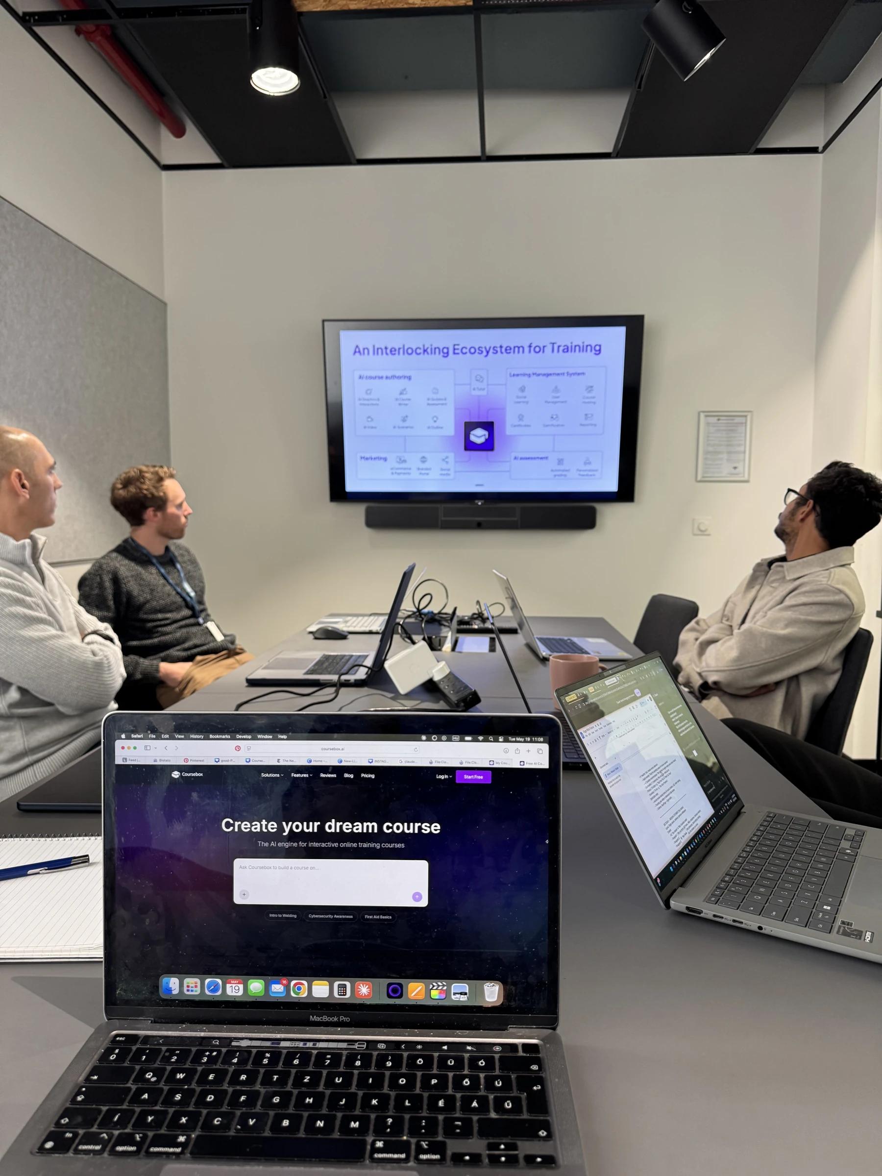 The Coursebox AI team looking at a strategy slide on the meeting room screen during the weekly team meeting