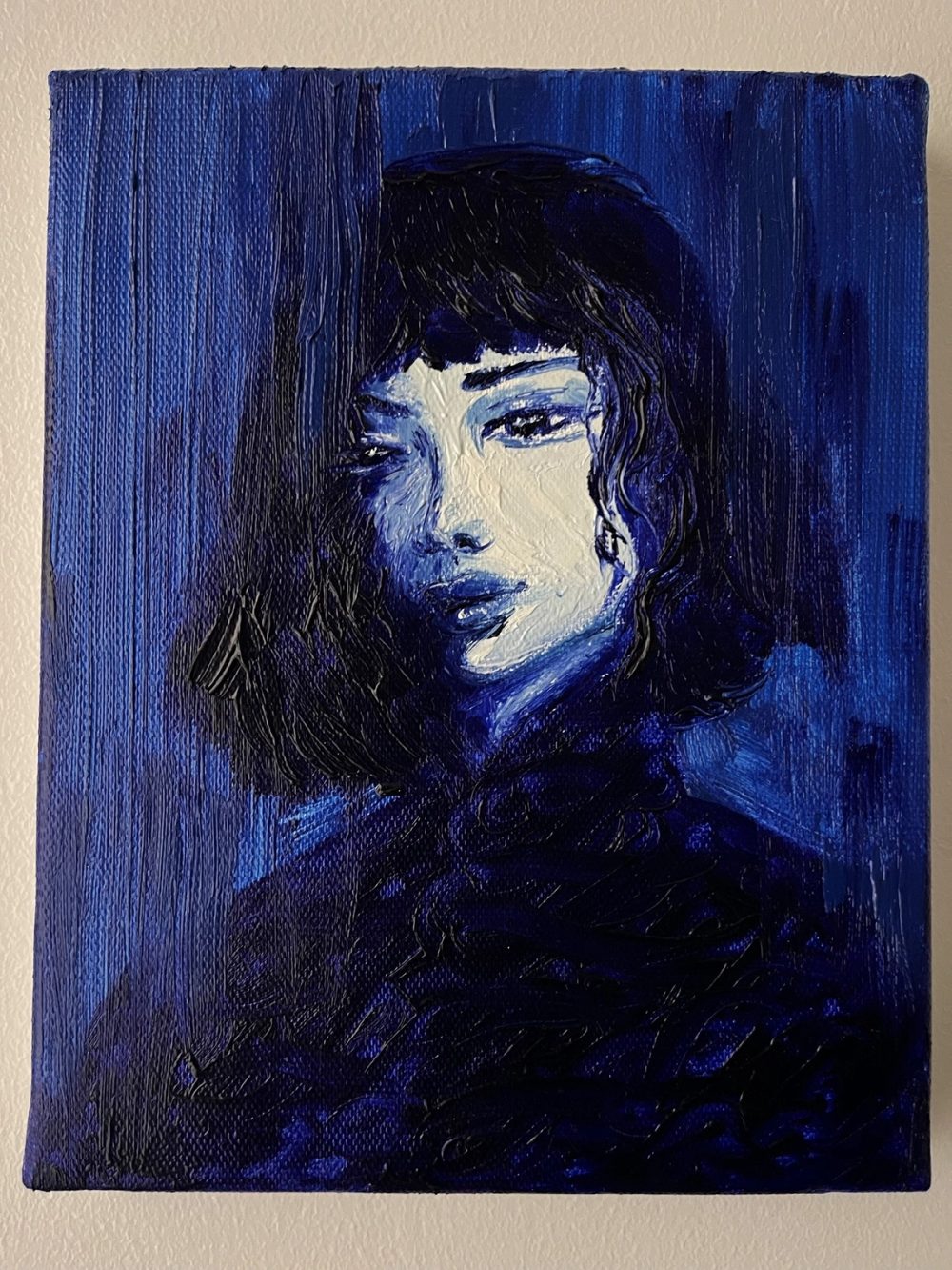 Roma : portrait de femme à la frange sombre, regard en biais, peint en bleu profond.