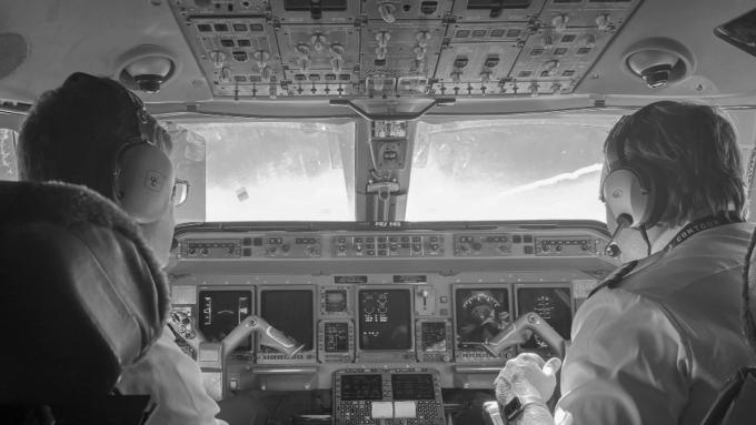 The view from behind two pilots in an aircraft cockpit
