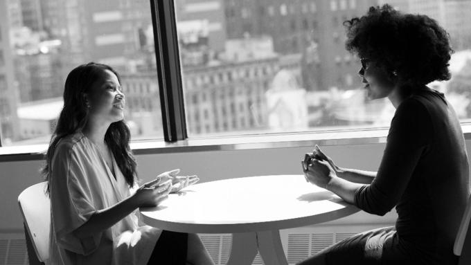 Two people in conversation at a table by a window