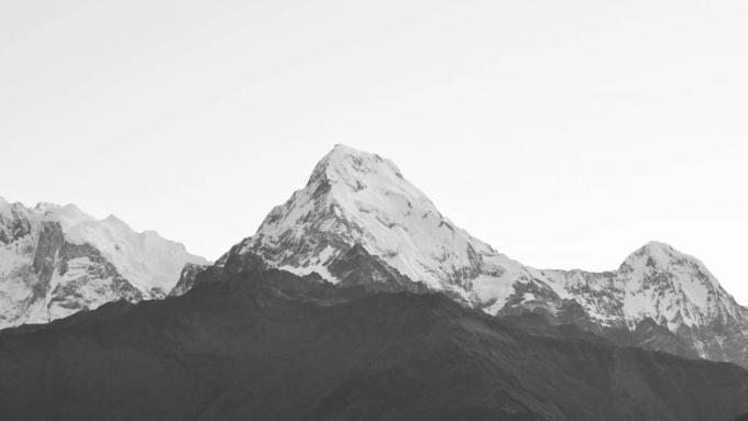 A snow-covered Himalayan peak against a pale sky
