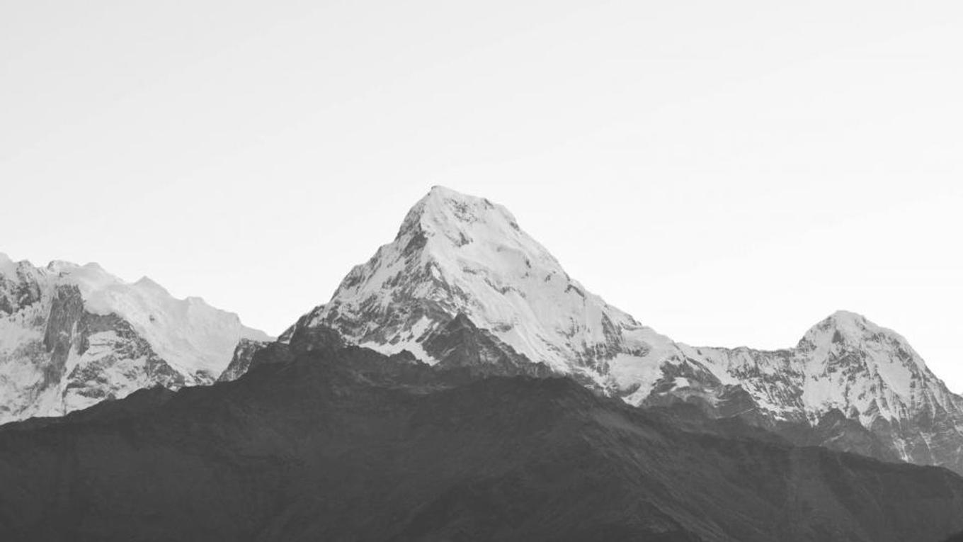 A snow-covered Himalayan peak against a pale sky