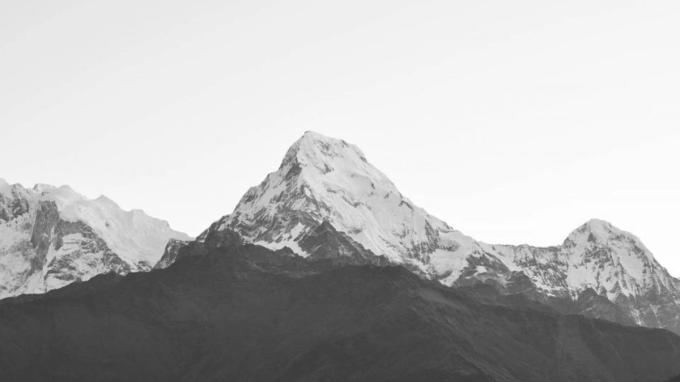 A snow-covered Himalayan peak against a pale sky