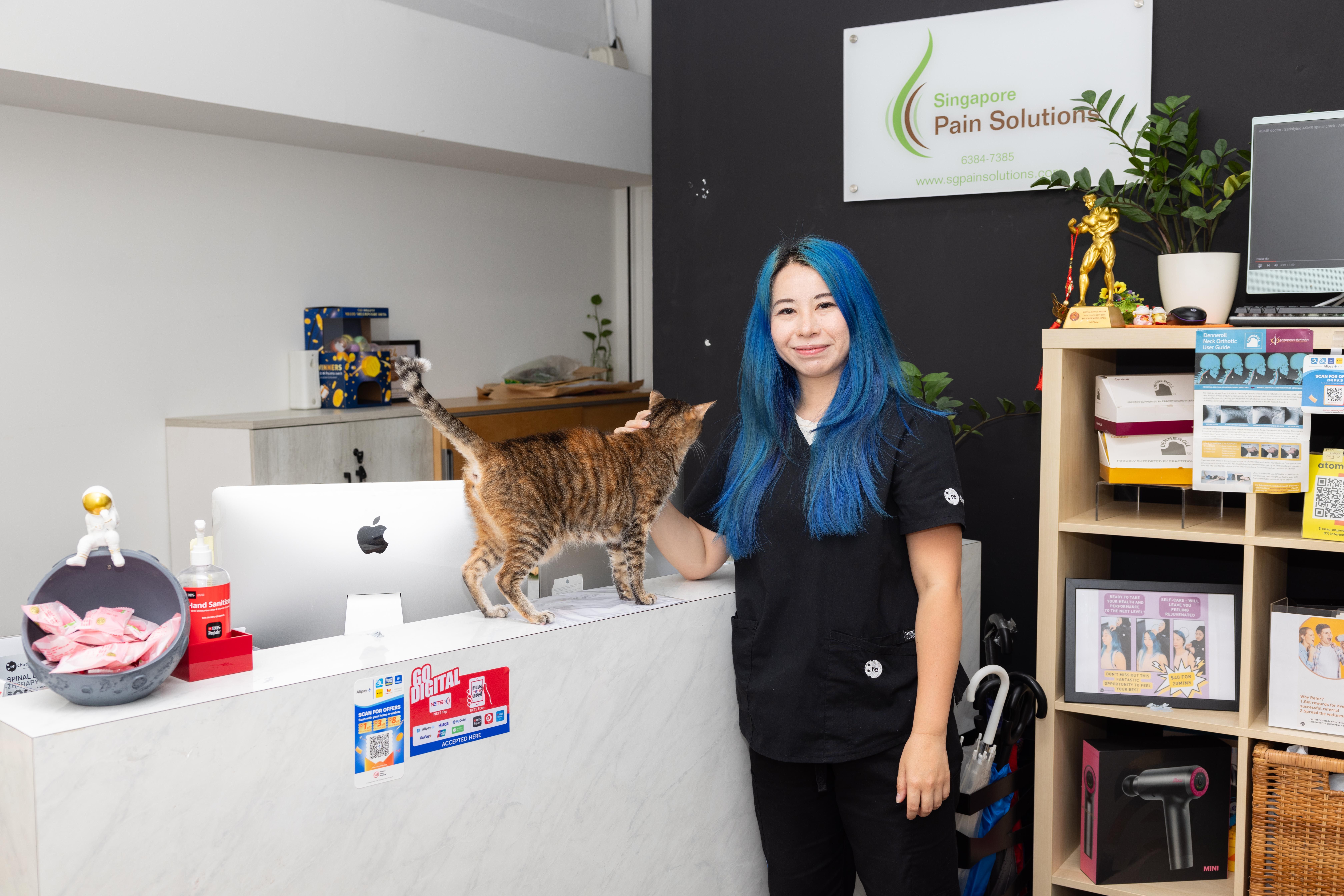 Dr Jenny Li stands at the reception desk with a cat.