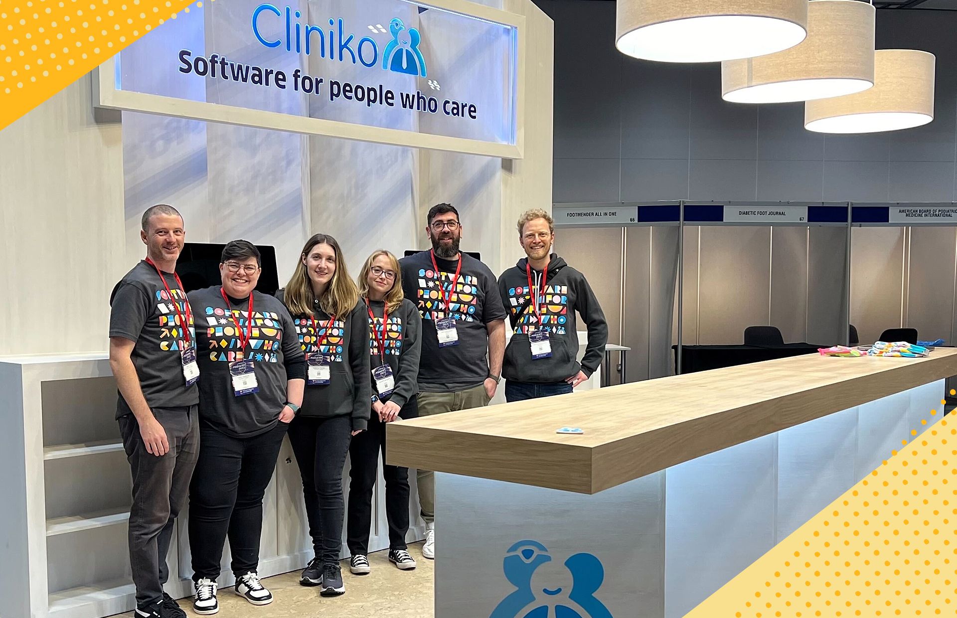 A photo of the team posing in front of the Cliniko stand at Podiatry 2023