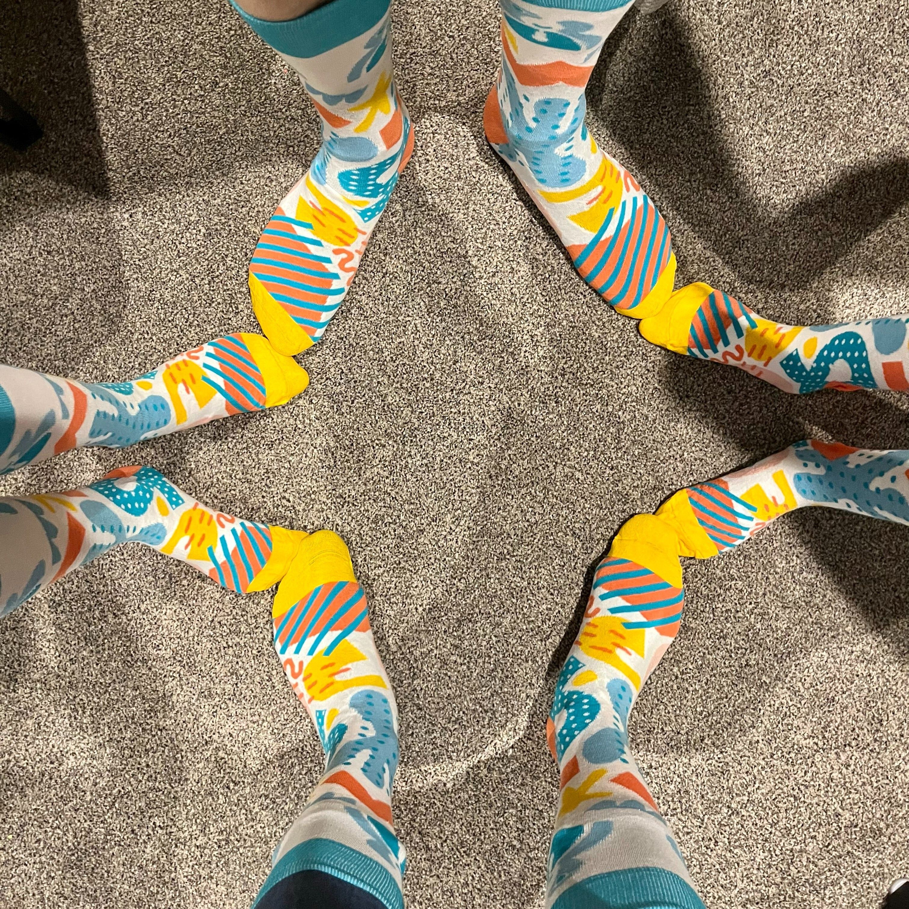 Feet wearing Cliniko branded socks posed in the shape of a star