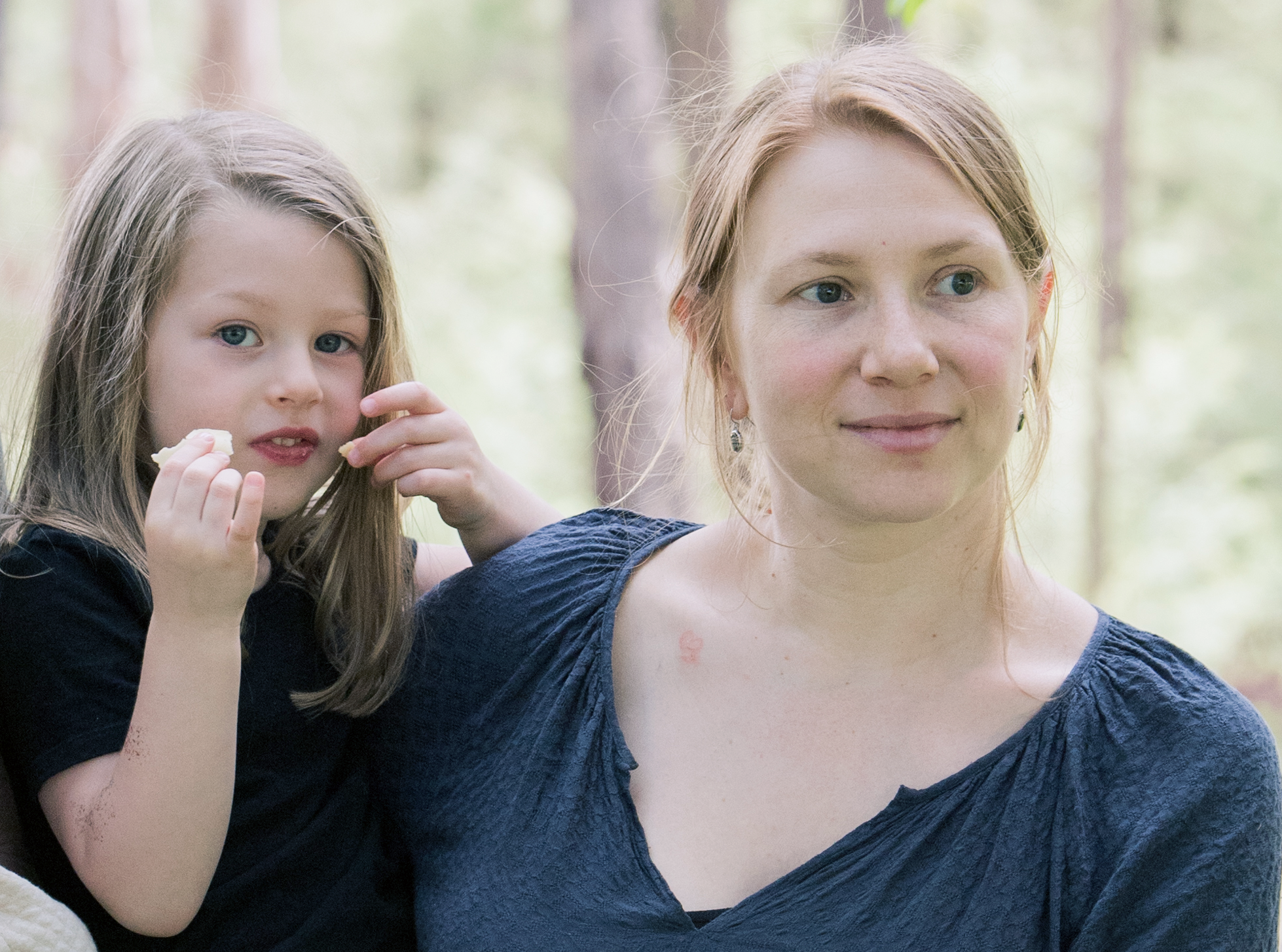 Portrait of osteopath and Cliniko founder Liora Dafner-Beach holding her daughter in a wooded area
