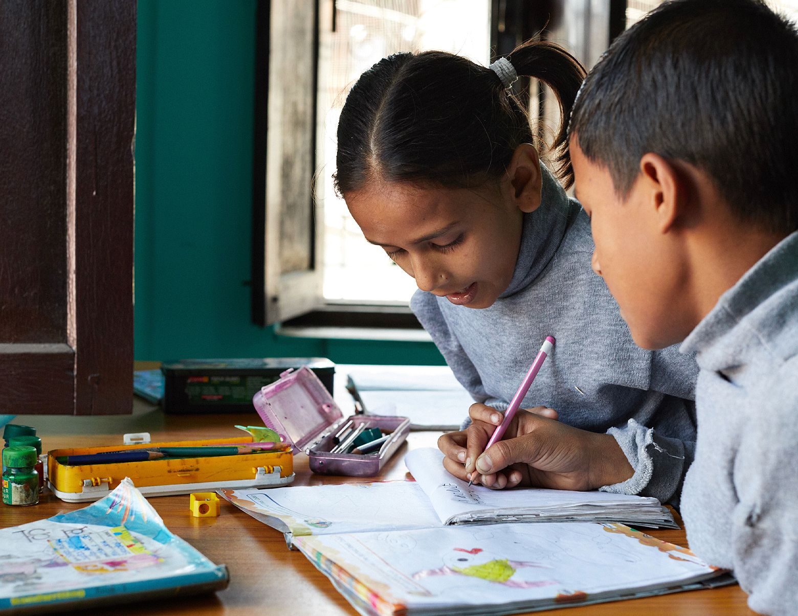 Two children at a Beyond the Orphanage home doing school work together.