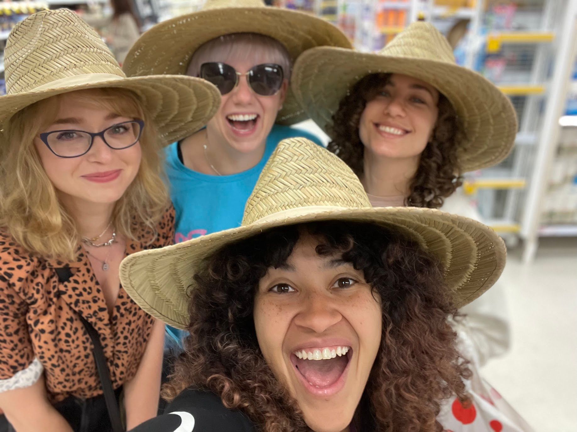 A photo with four of the Cliniko team visiting a shop, wearing matching straw hats