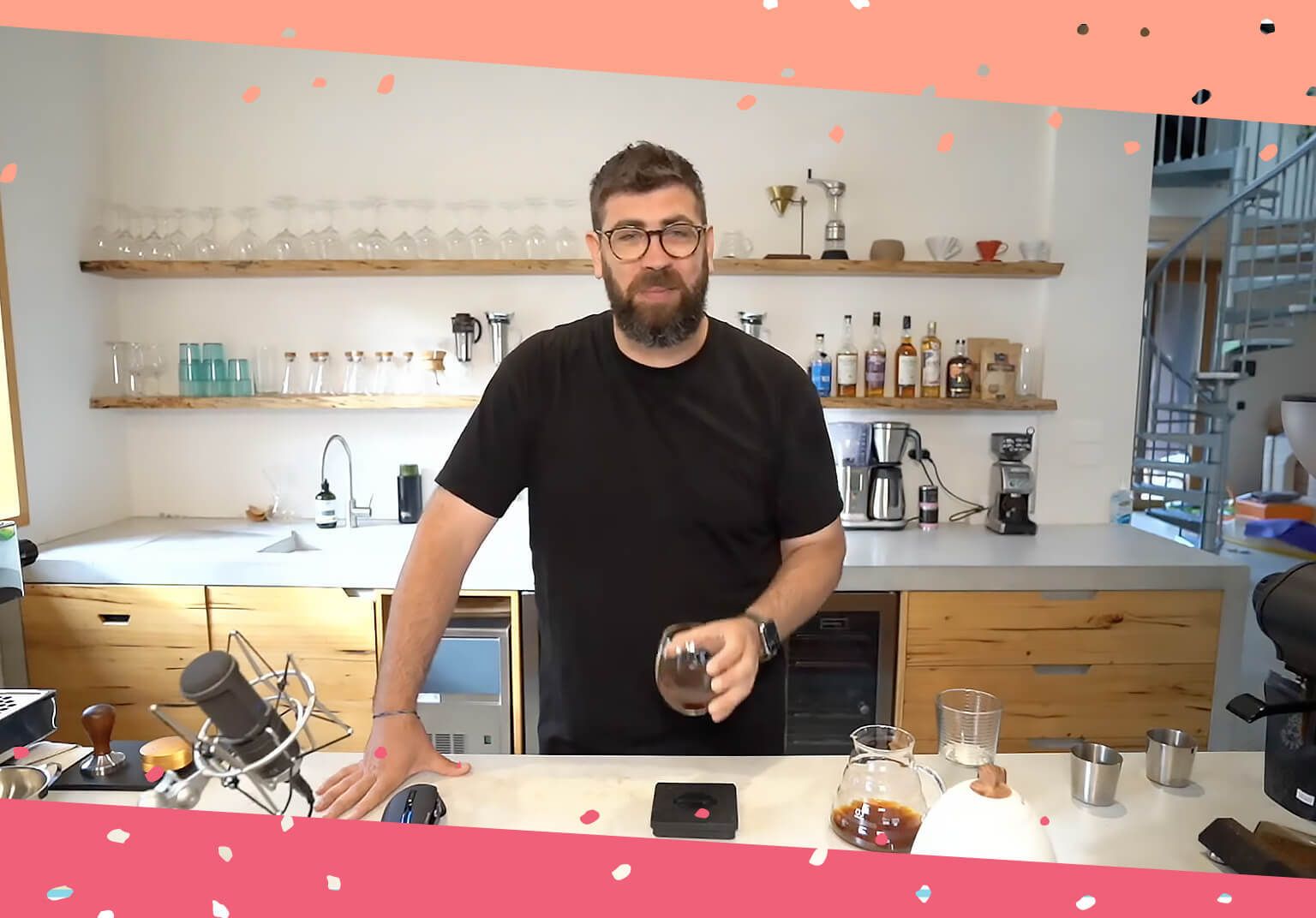 Joel standing in his kitchen holding a cup of coffee, surrounded by coffee-making tools