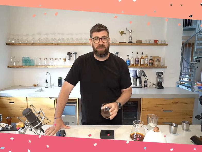 Joel standing in his kitchen holding a cup of coffee, surrounded by coffee-making tools
