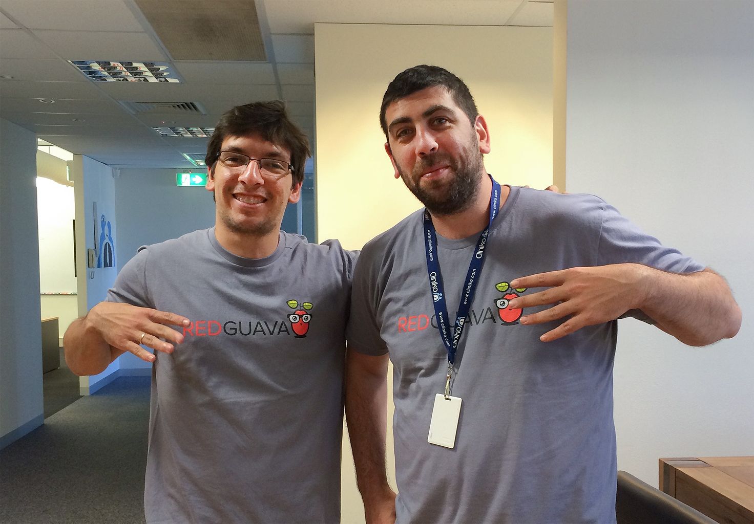 Two members of the Cliniko team wearing 'Red Guava' t-shirts in our first office in Melbourne.
