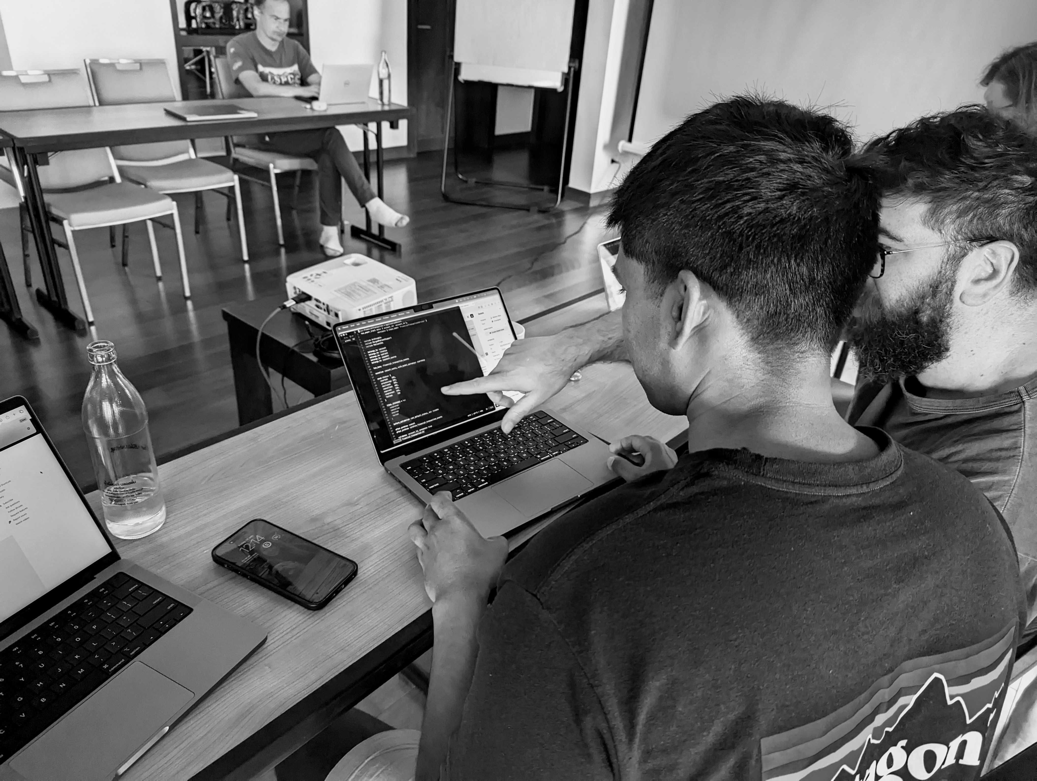 Joel and Fahad looking at a laptop screen together in the Phuket team workroom