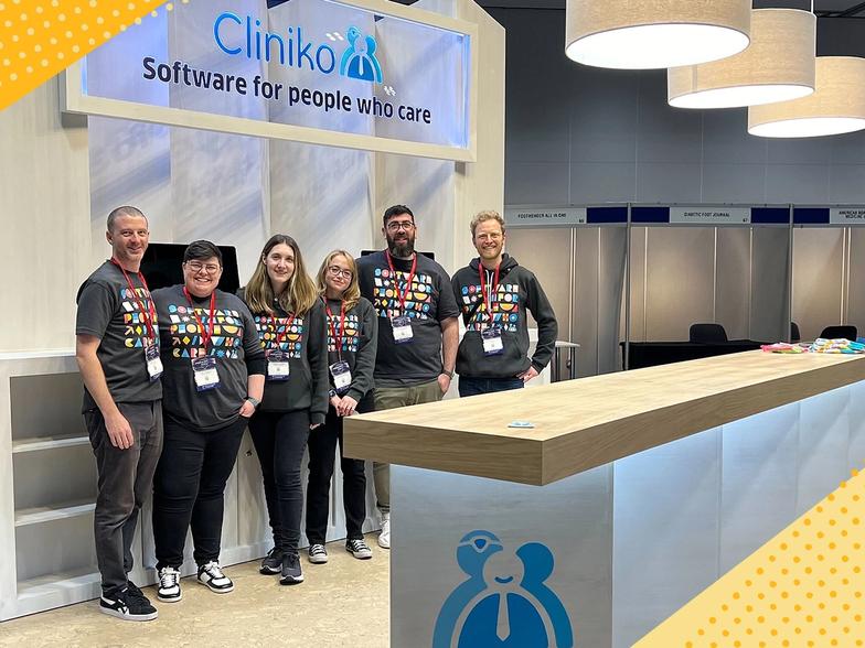 A photo of the team posing in front of the Cliniko stand at Podiatry 2023
