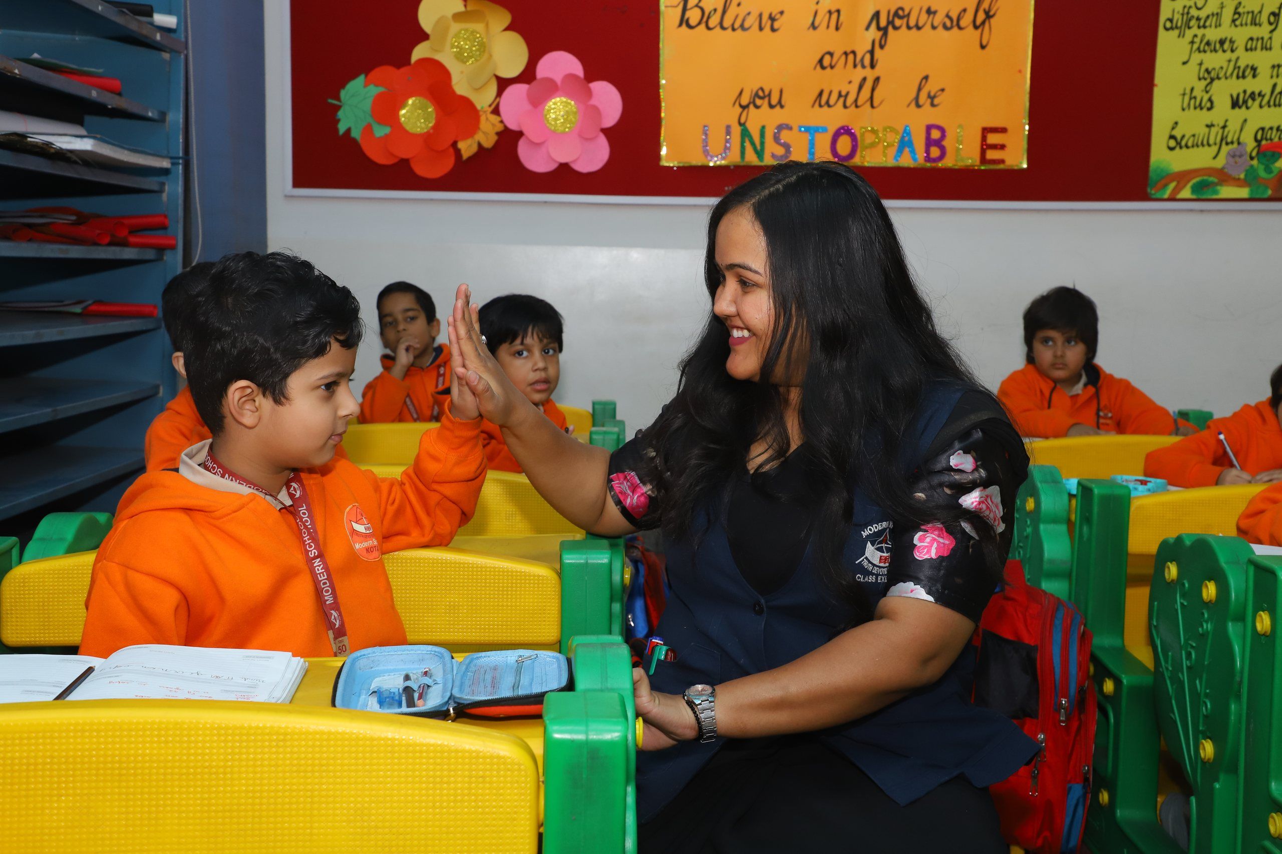 A teacher giving a young pupil a high five in class
