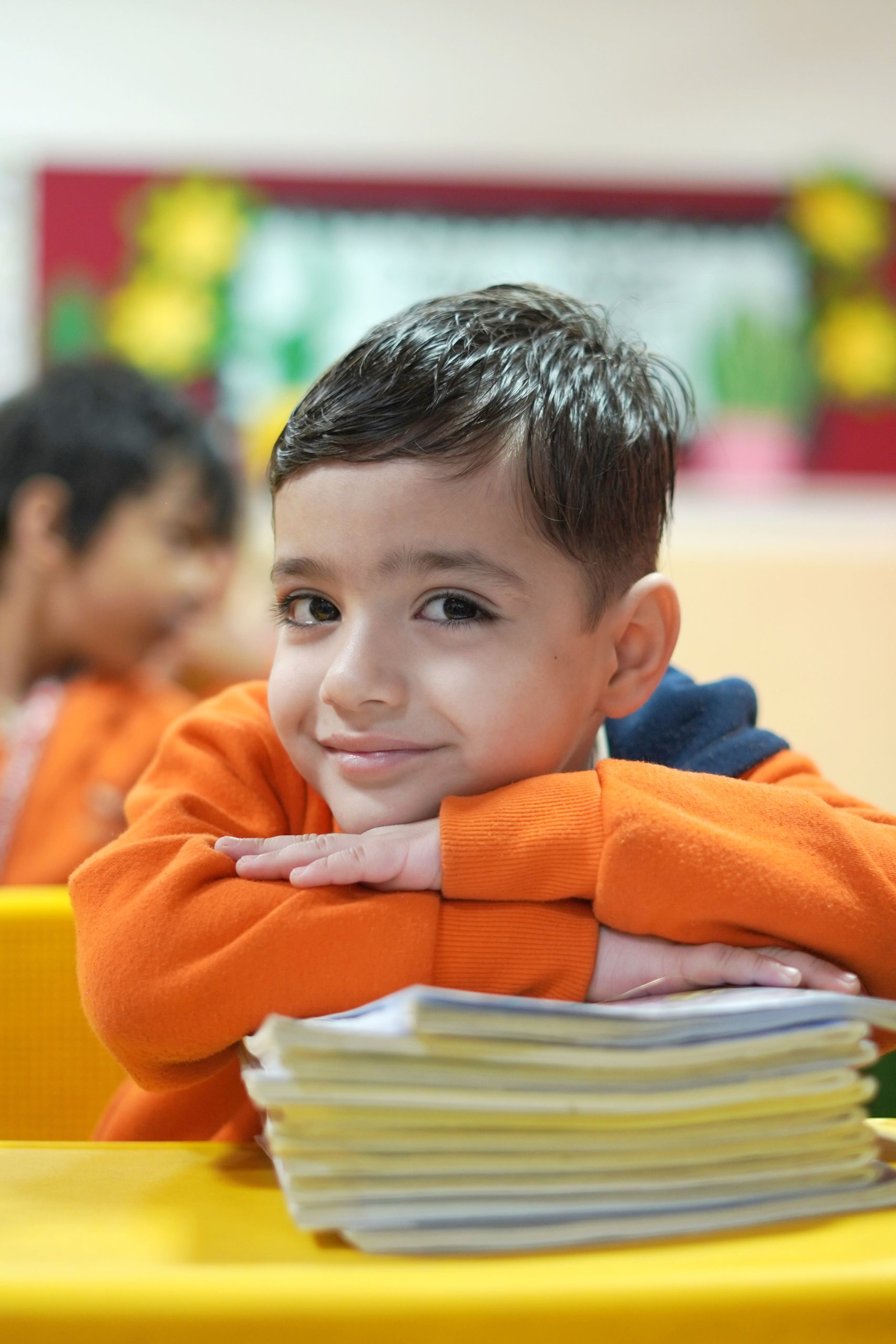A pre-primary boy smiling over his notebooks