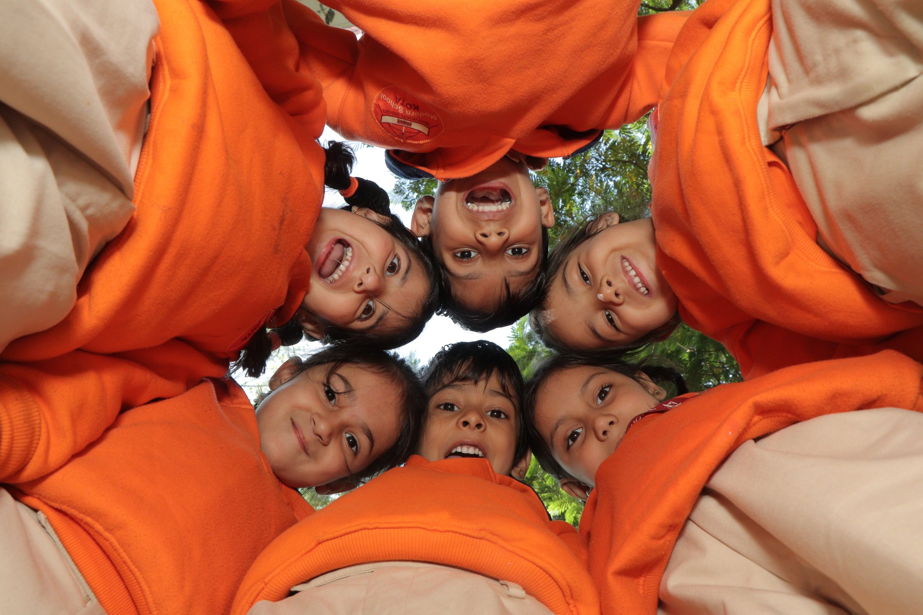 Pre-primary children in a huddle, smiling down at the camera