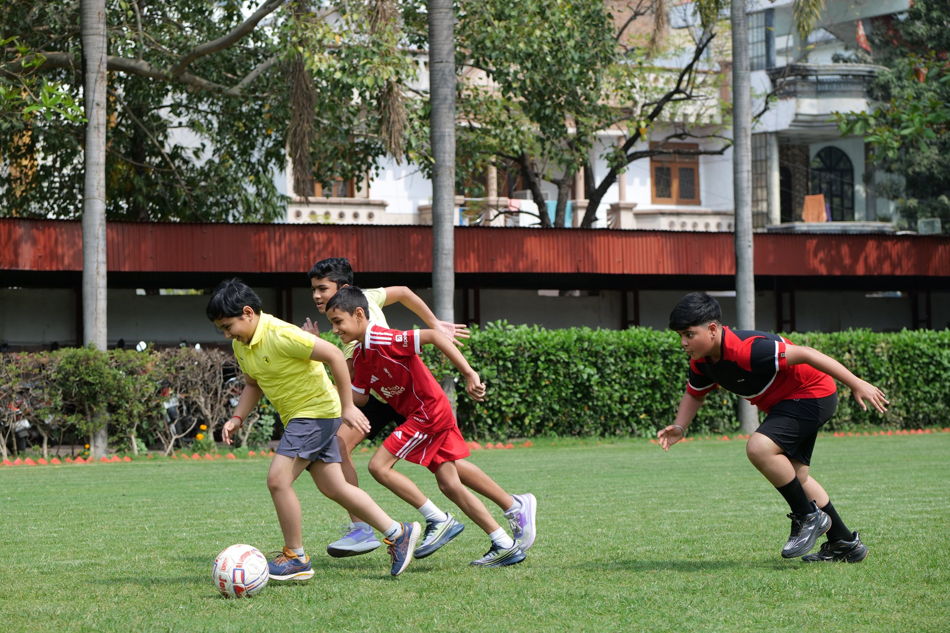 Students chasing the ball in a football game on the lawn