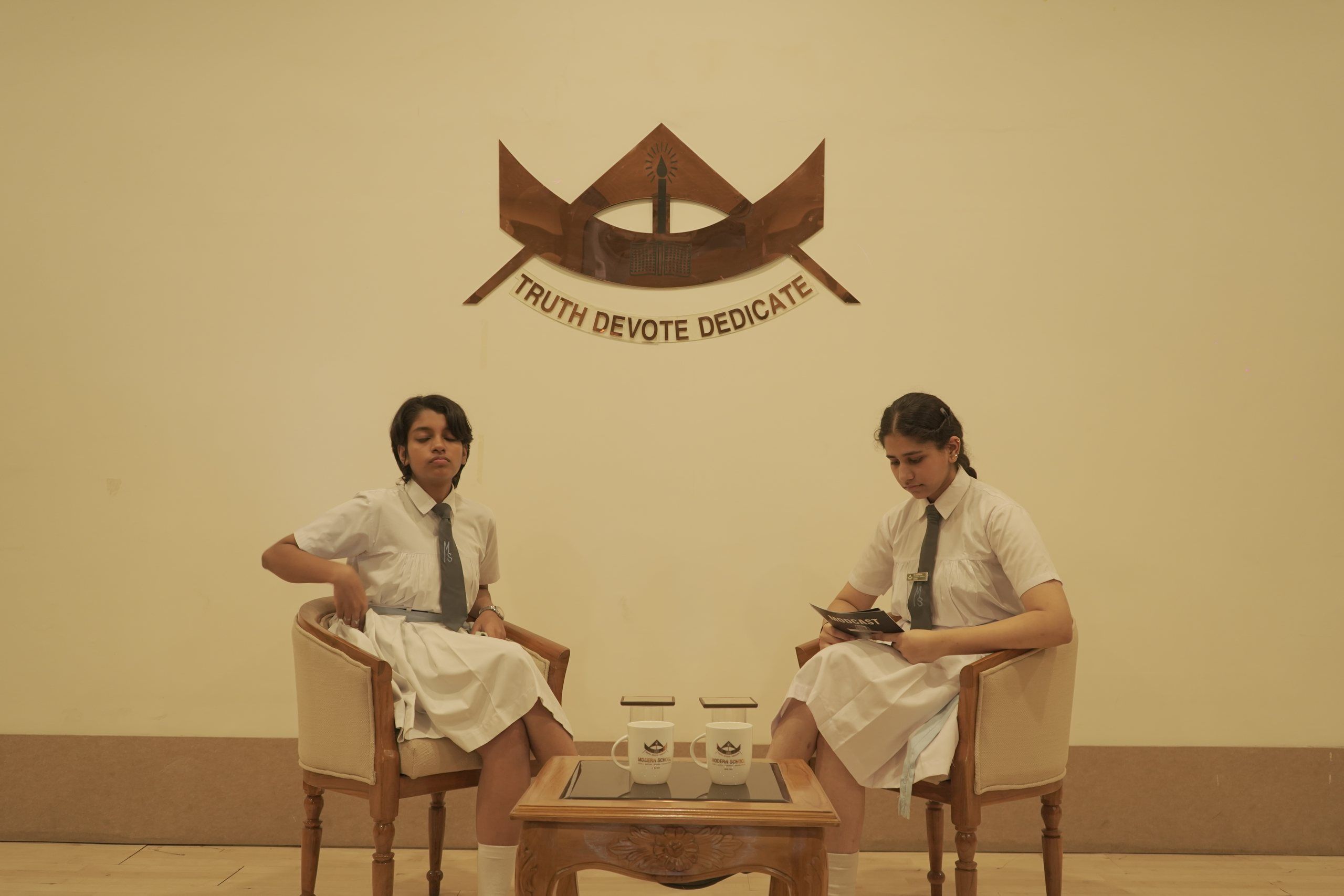 Two students recording the school podcast beneath the school crest