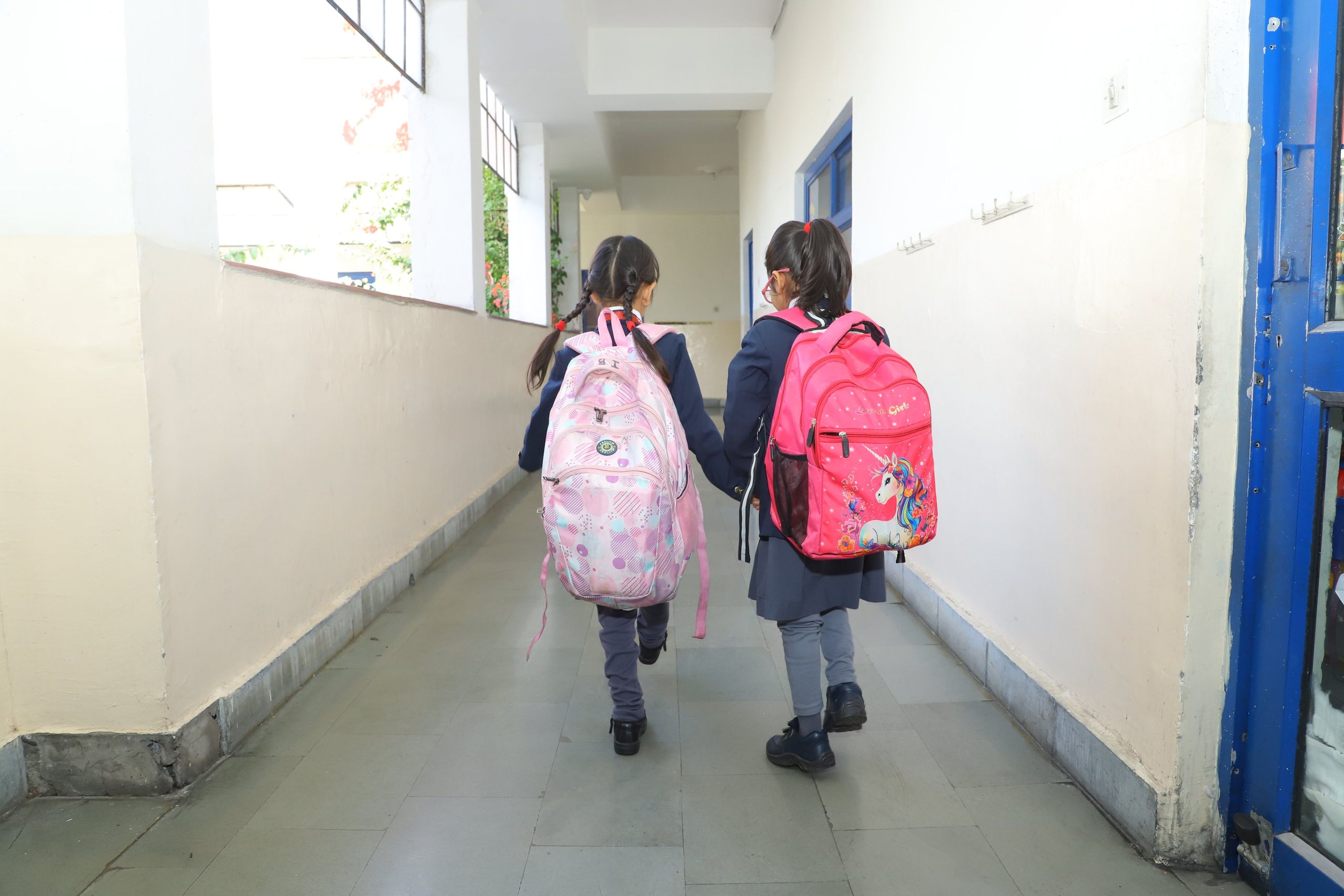 Two pupils walking down a school corridor with their bags
