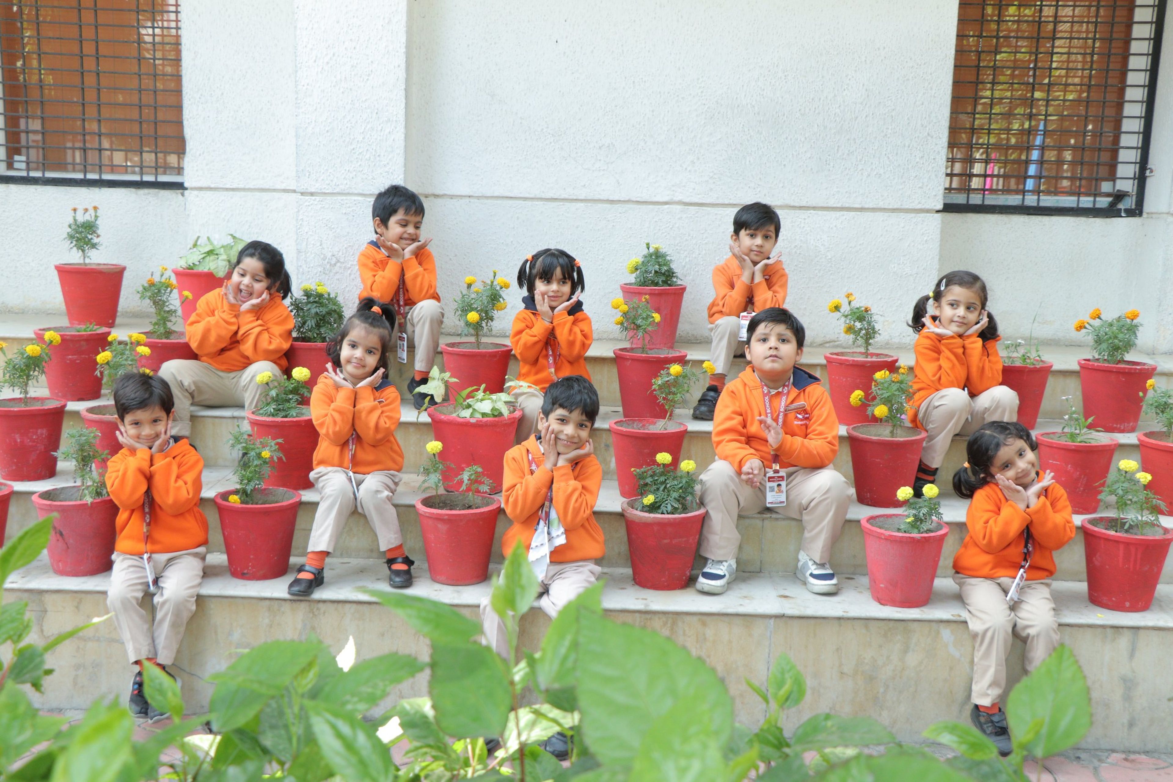 Pre-primary children sitting on the garden steps among flower pots