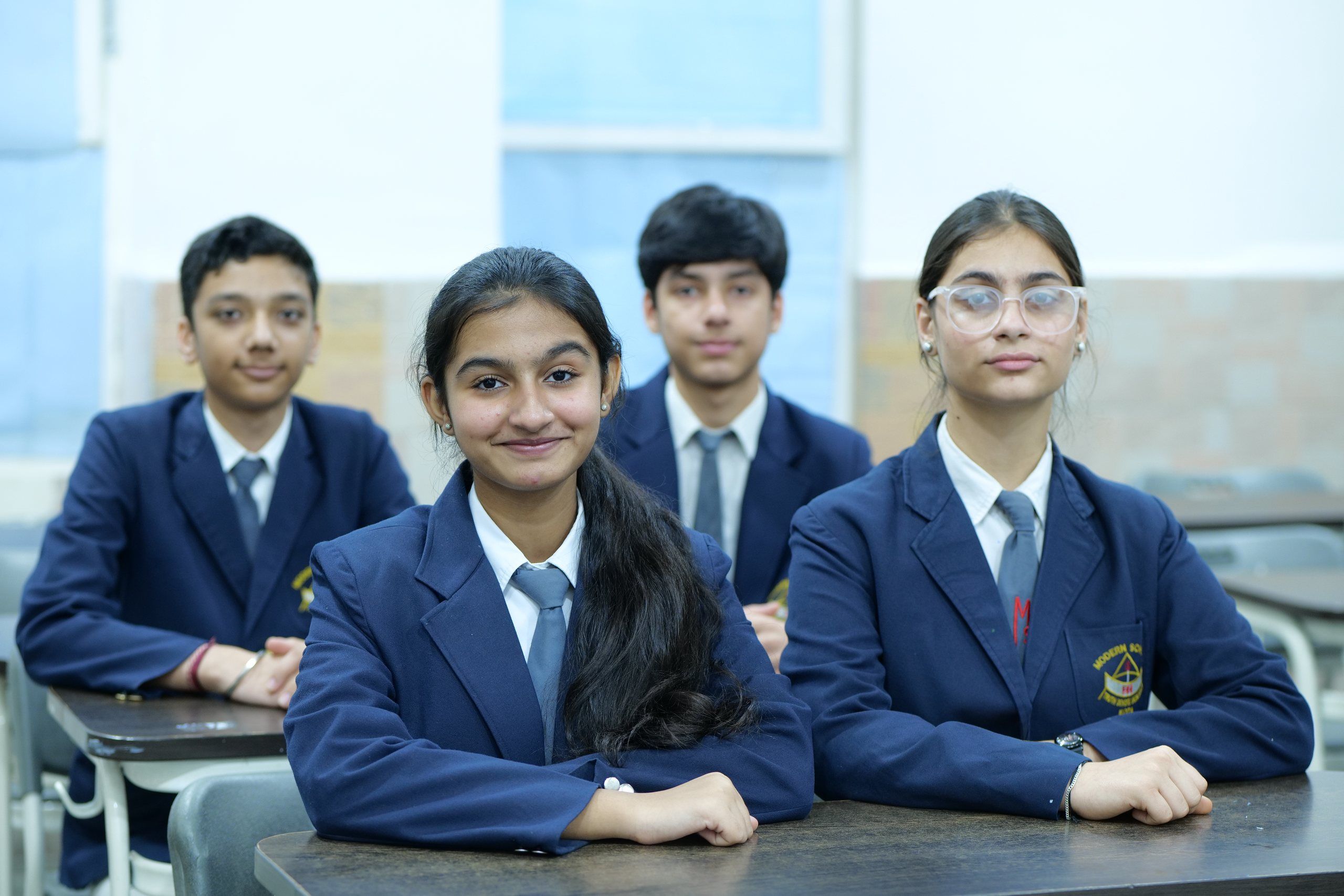 Four senior students in school blazers at their desks