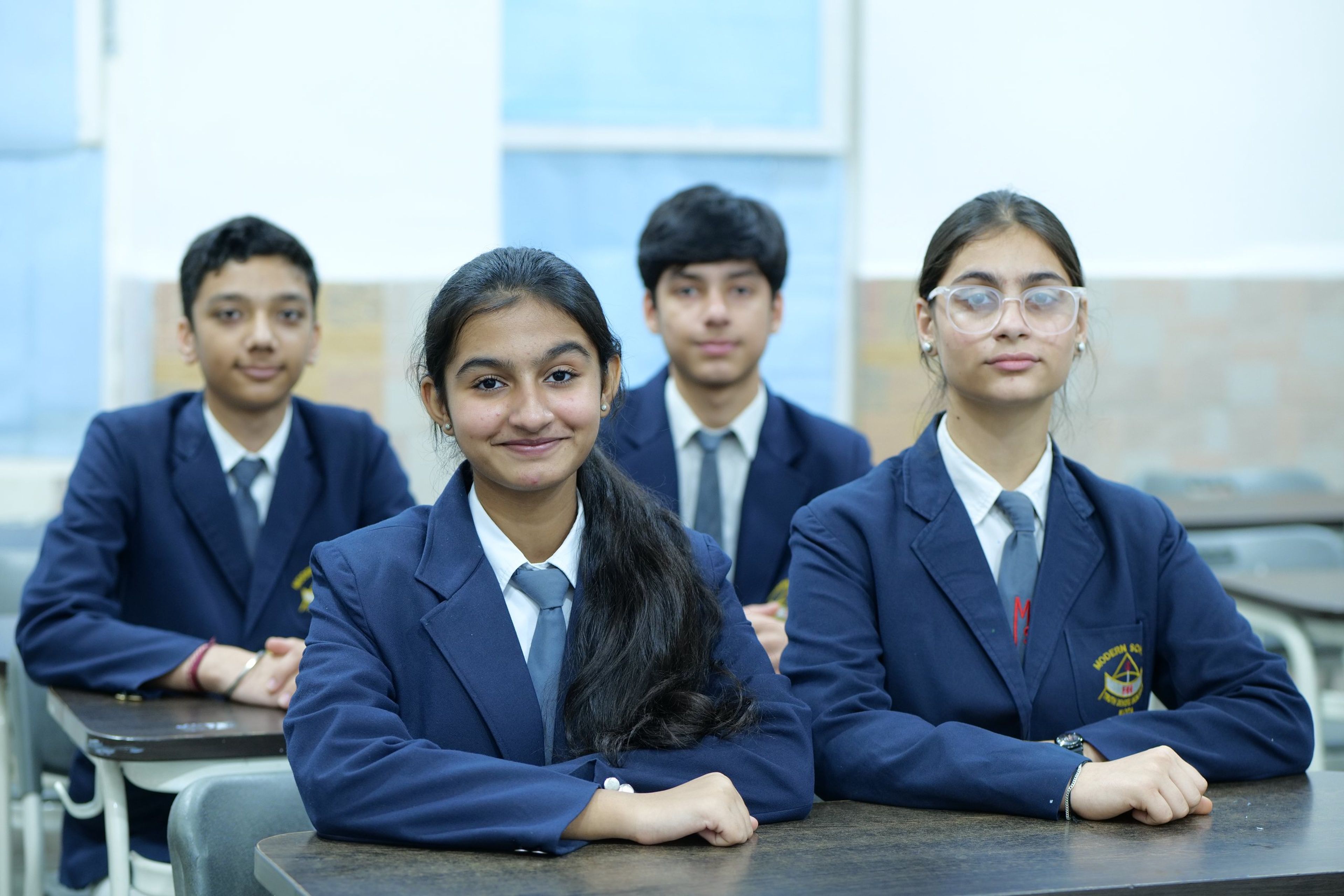 Four senior students in school blazers at their desks