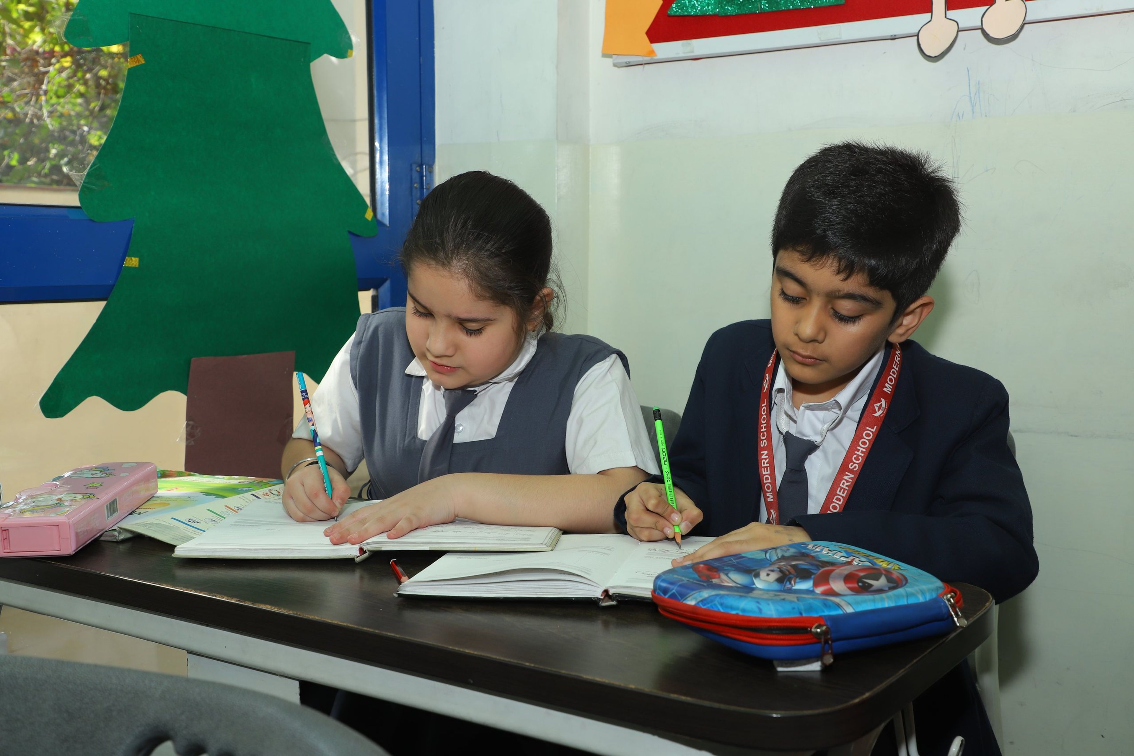 Two primary pupils writing in their notebooks