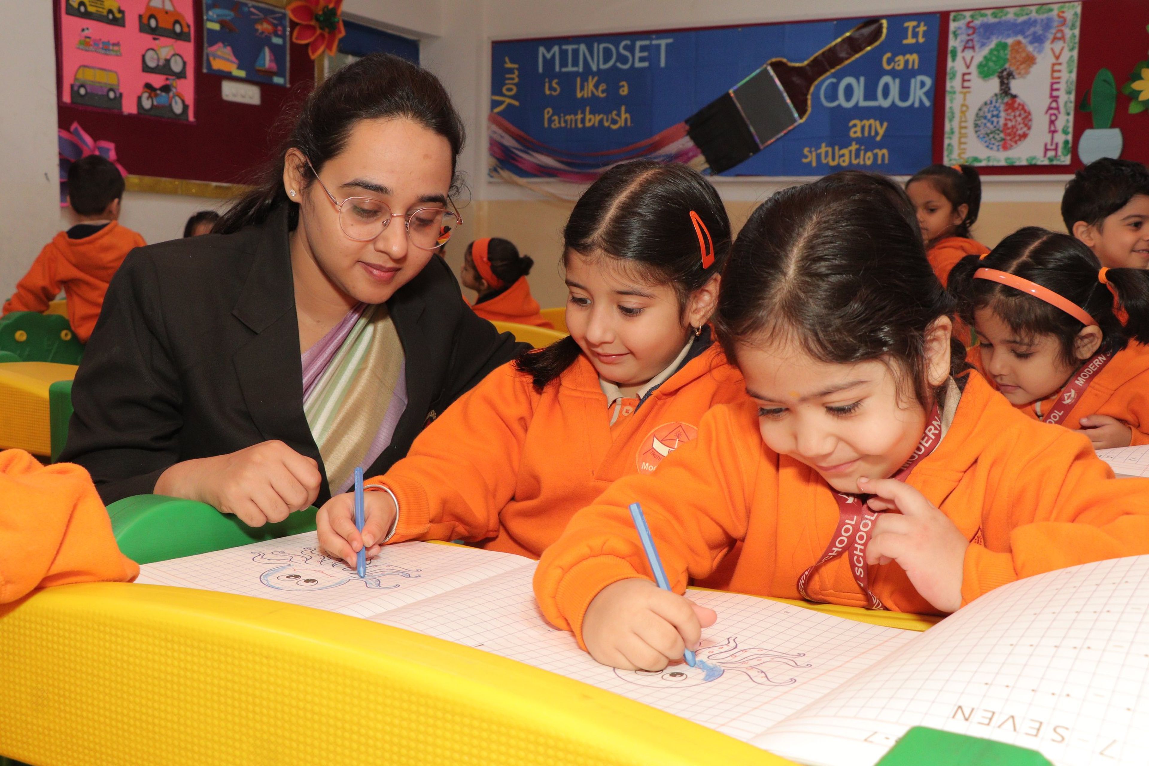 A teacher guiding young pupils as they write