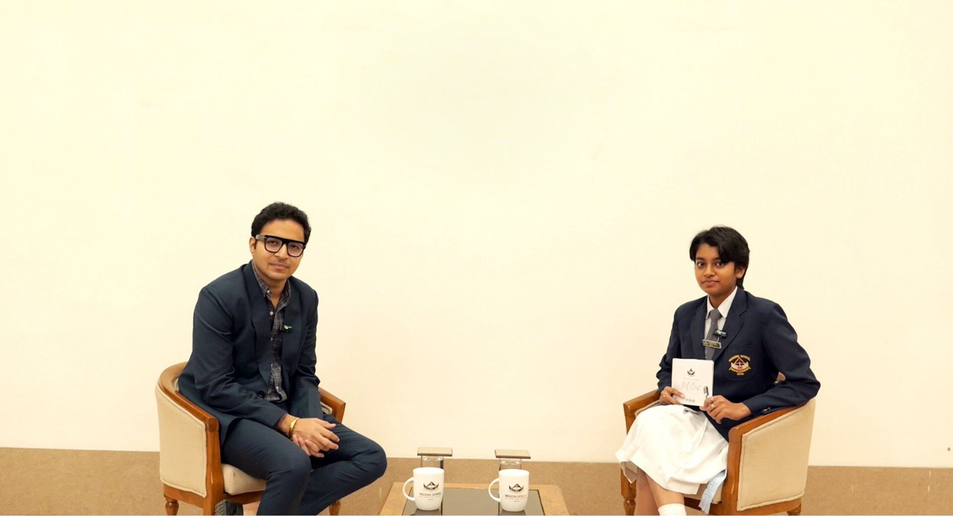 A guest in conversation with a student host on the podcast set