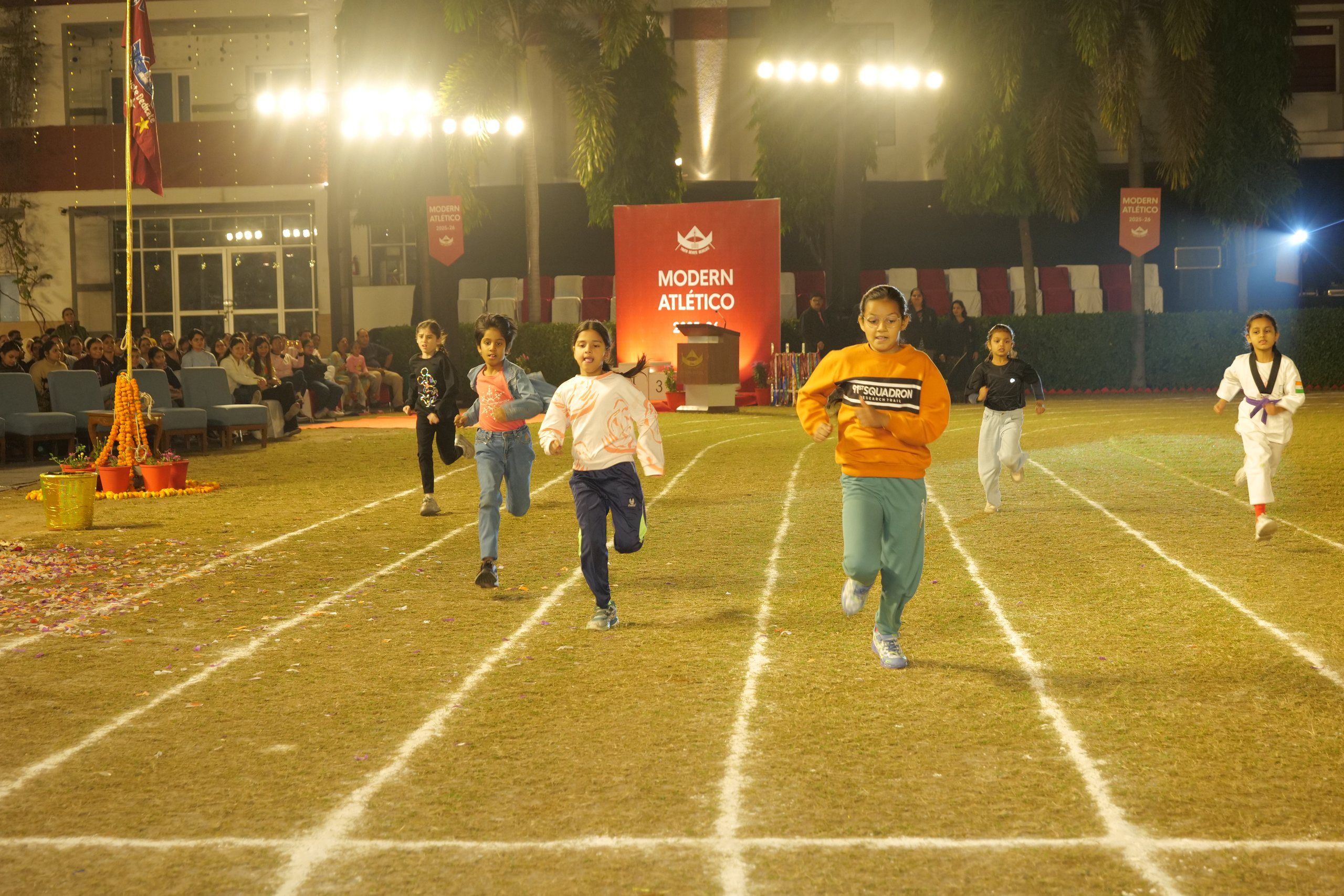 Students racing on the floodlit field at the school sports meet