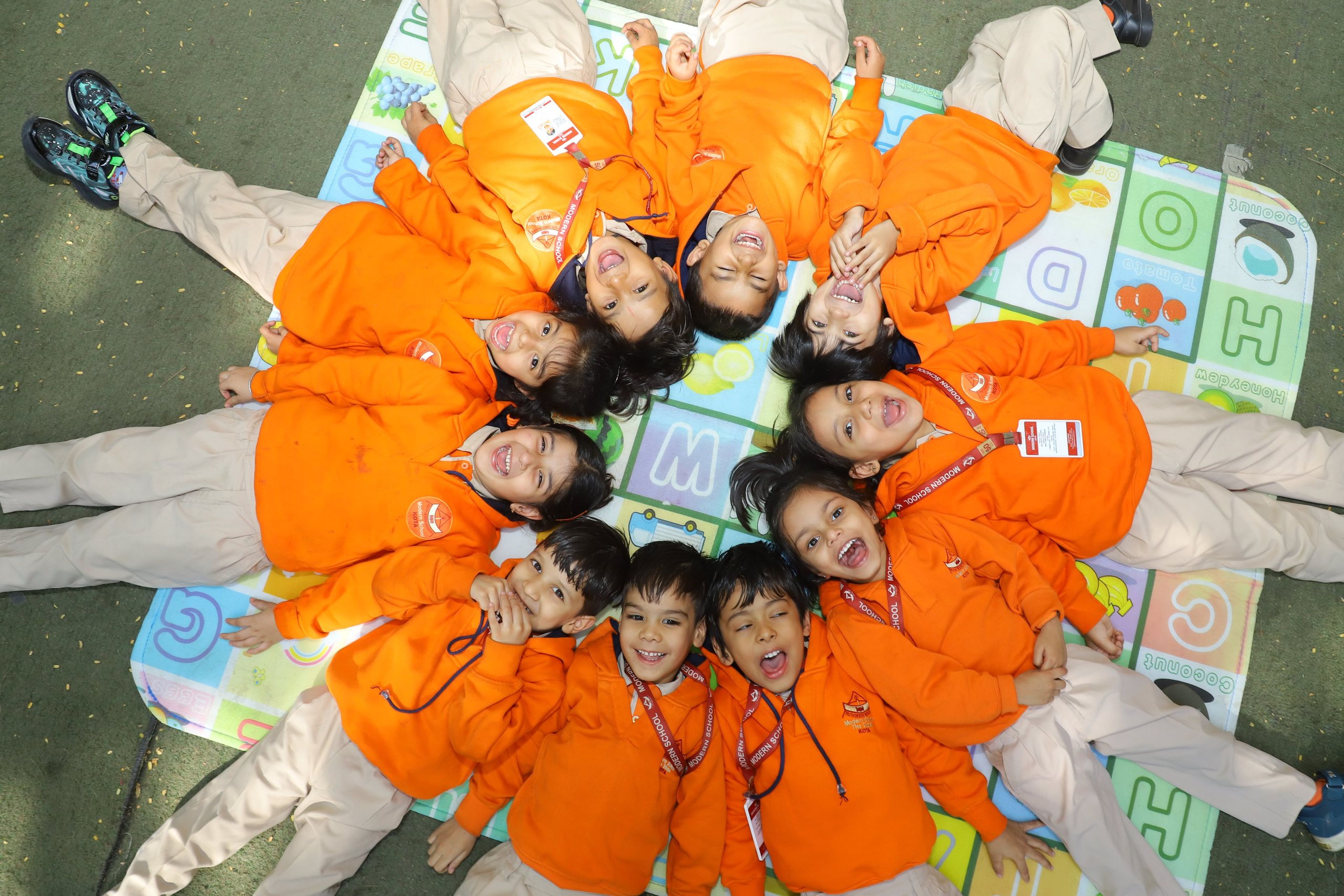 Pre-primary children lying in a circle and smiling up at the camera