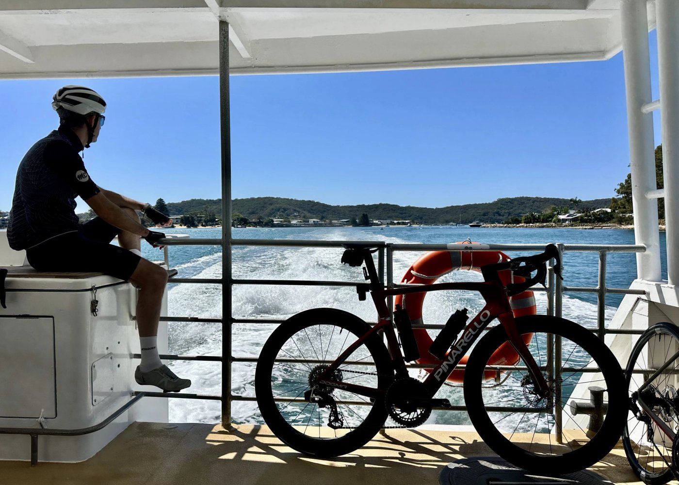 Bikes resting against the rail on the ferry, wake and the far shore behind