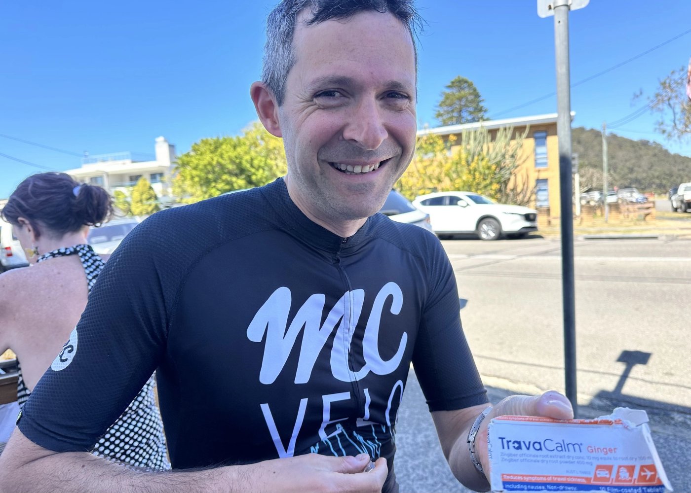 A rider in an MC Velo jersey holding up a packet of travel sickness tablets at Ettalong