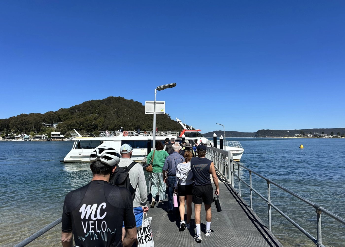 Riders and other passengers walking down the wharf at Ettalong towards the waiting ferry