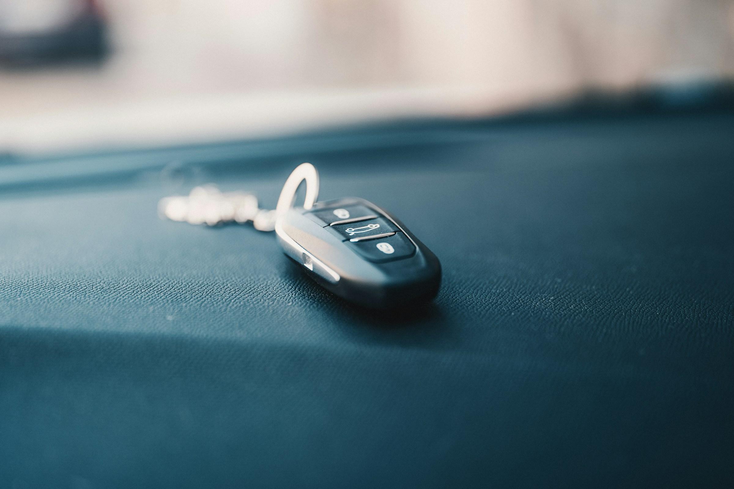 Black car key fob resting on a vehicle dashboard with a softly blurred background